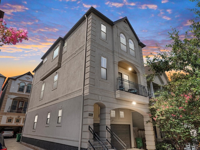 view of front of property featuring stucco siding, a balcony, and an attached garage