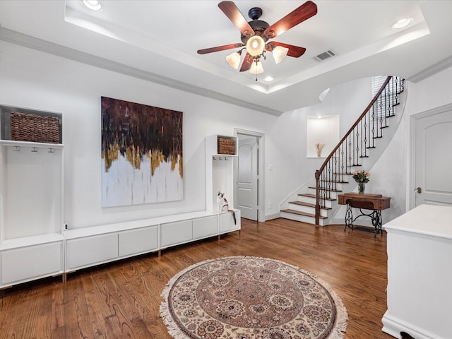 entryway featuring visible vents, a tray ceiling, wood finished floors, recessed lighting, and stairs