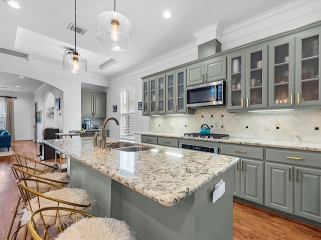 kitchen featuring visible vents, gray cabinetry, appliances with stainless steel finishes, arched walkways, and a sink