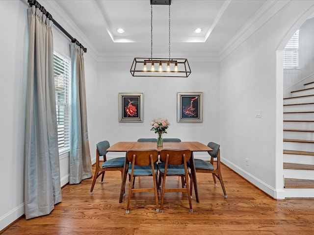 dining room featuring stairs, a tray ceiling, and wood finished floors