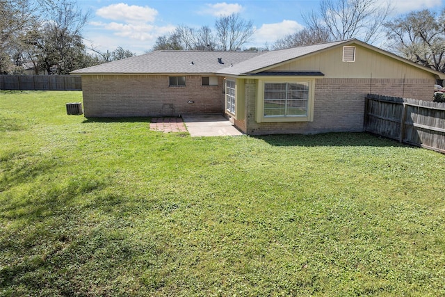 back of property with brick siding, fence, central air condition unit, a yard, and a patio area