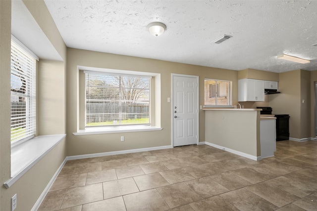 interior space with visible vents, black range with electric cooktop, baseboards, a peninsula, and white cabinets