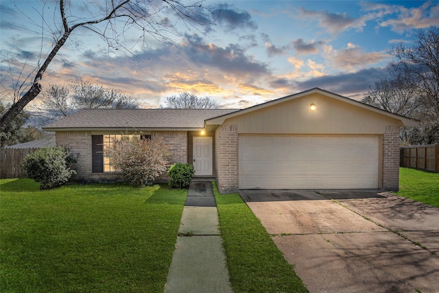 view of front facade featuring a garage, brick siding, a front yard, and fence