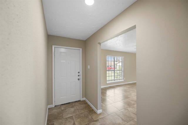 entrance foyer featuring light tile patterned floors, a textured ceiling, and baseboards