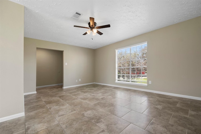 unfurnished room featuring visible vents, a textured ceiling, baseboards, and ceiling fan