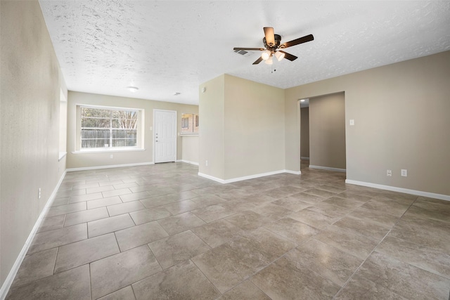 unfurnished living room with ceiling fan, baseboards, and a textured ceiling