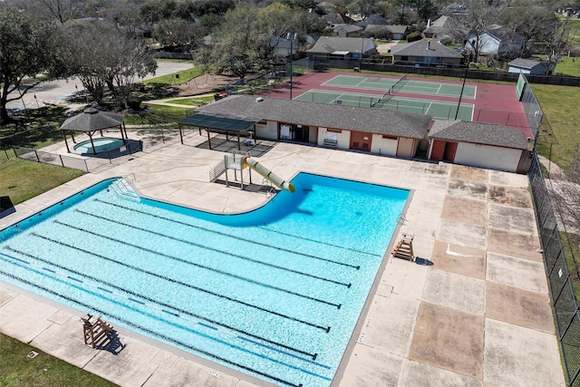 community pool with a patio area and fence