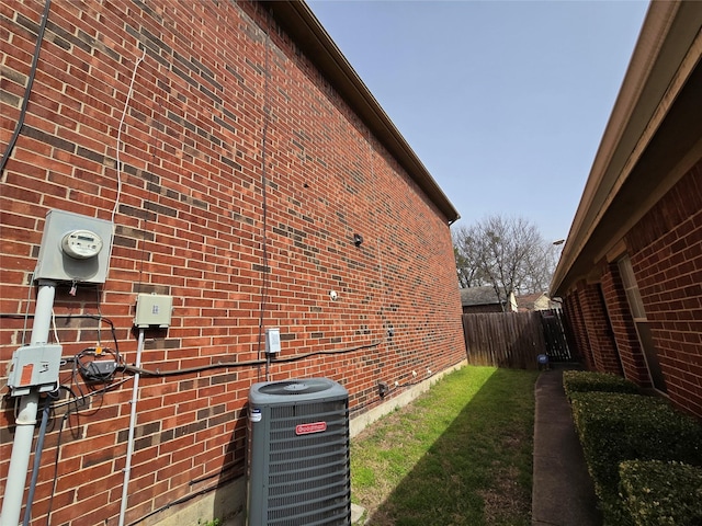 view of home's exterior with brick siding, central AC unit, and fence