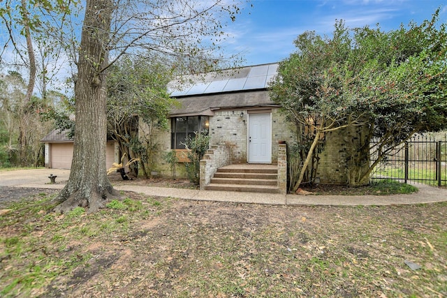 view of front of house featuring fence, solar panels, a shingled roof, a garage, and brick siding