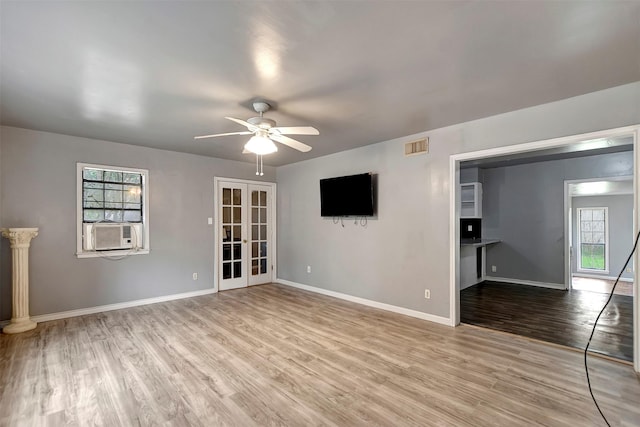 interior space featuring cooling unit, baseboards, light wood finished floors, ceiling fan, and french doors