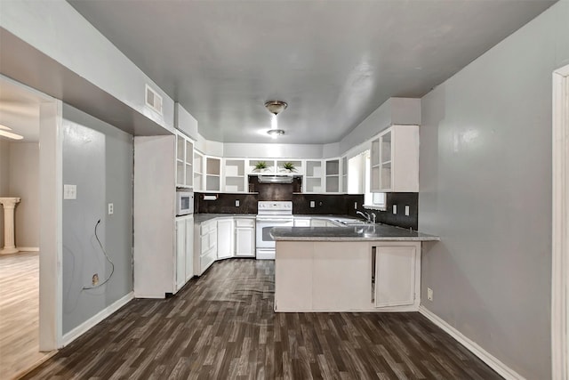 kitchen featuring white appliances, a peninsula, open shelves, a sink, and tasteful backsplash