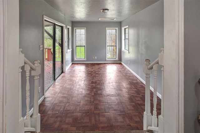 foyer entrance featuring a textured ceiling, stairs, and baseboards