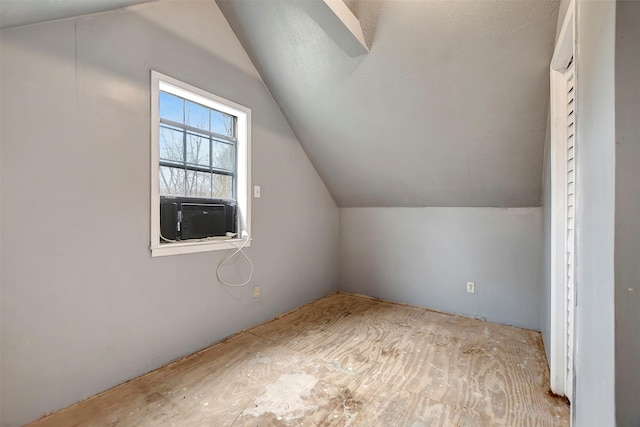 additional living space featuring cooling unit and lofted ceiling