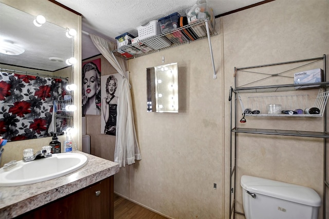 bathroom with vanity, toilet, wood finished floors, and a textured ceiling