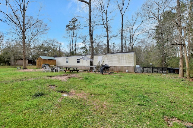 back of property featuring a shed, a lawn, an outdoor structure, and fence