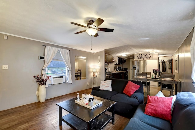 living area with a textured ceiling, wood finished floors, cooling unit, lofted ceiling, and ceiling fan