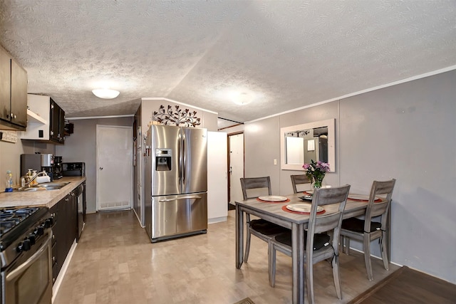 kitchen with light wood-style flooring, a sink, stainless steel appliances, light countertops, and vaulted ceiling
