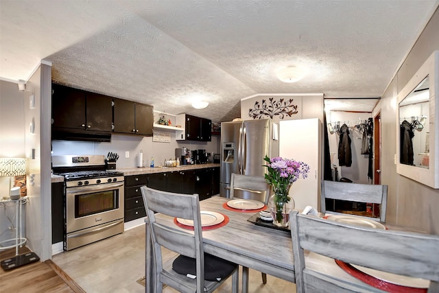 kitchen featuring dark brown cabinets, light countertops, vaulted ceiling, appliances with stainless steel finishes, and light wood-style floors