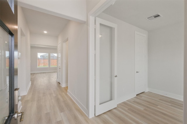 corridor with baseboards, visible vents, and light wood-type flooring