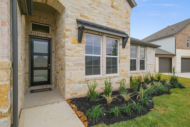 property entrance featuring a garage and stone siding