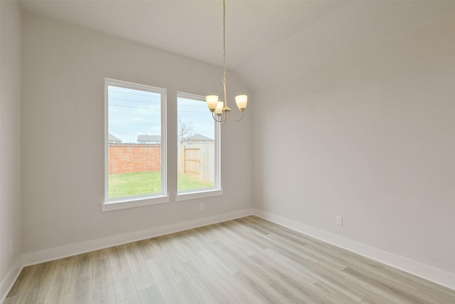 unfurnished room featuring baseboards, a notable chandelier, and light wood finished floors