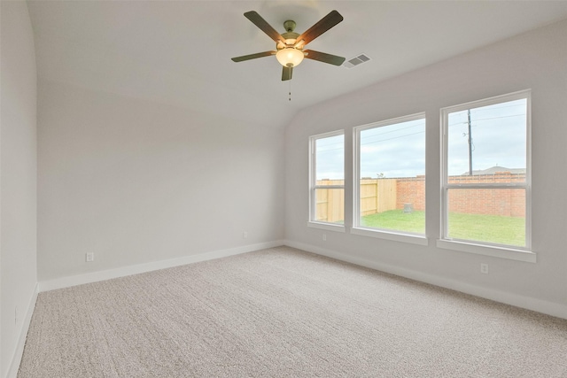 carpeted empty room featuring vaulted ceiling, baseboards, visible vents, and ceiling fan