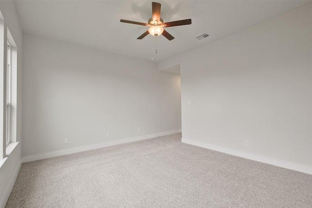 carpeted empty room featuring visible vents, baseboards, and a ceiling fan