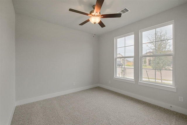 empty room featuring ceiling fan, light colored carpet, visible vents, and baseboards