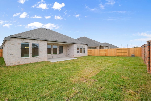 rear view of property featuring a patio area, a yard, a fenced backyard, and brick siding