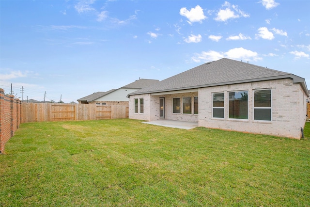 back of property with a yard, a fenced backyard, brick siding, and a patio