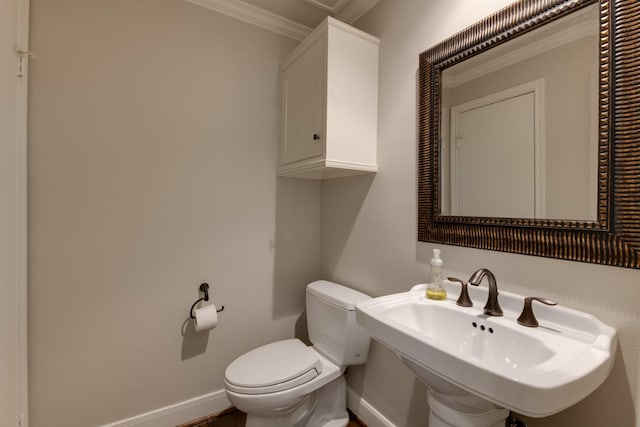 bathroom with crown molding, toilet, baseboards, and a sink