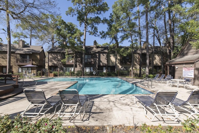 community pool featuring a patio area, a residential view, and fence