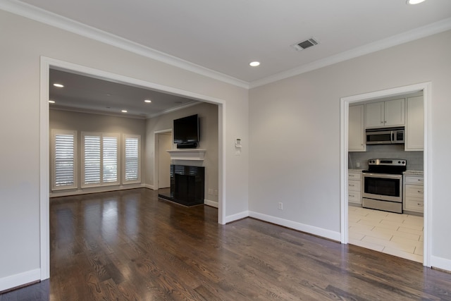 unfurnished living room featuring visible vents, a fireplace with raised hearth, crown molding, and wood finished floors