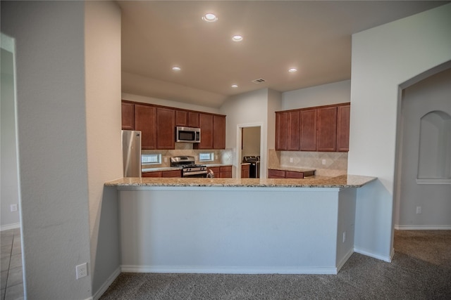 kitchen with light stone counters, visible vents, a peninsula, appliances with stainless steel finishes, and tasteful backsplash