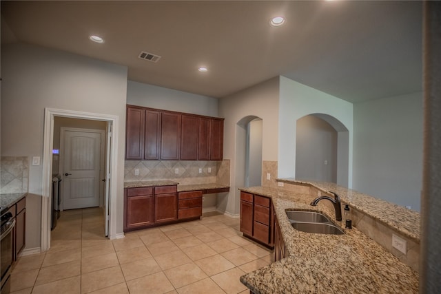 kitchen with visible vents, backsplash, light stone countertops, light tile patterned floors, and a sink