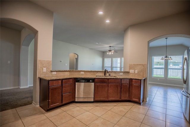 kitchen featuring light tile patterned floors, a healthy amount of sunlight, light stone countertops, a sink, and appliances with stainless steel finishes