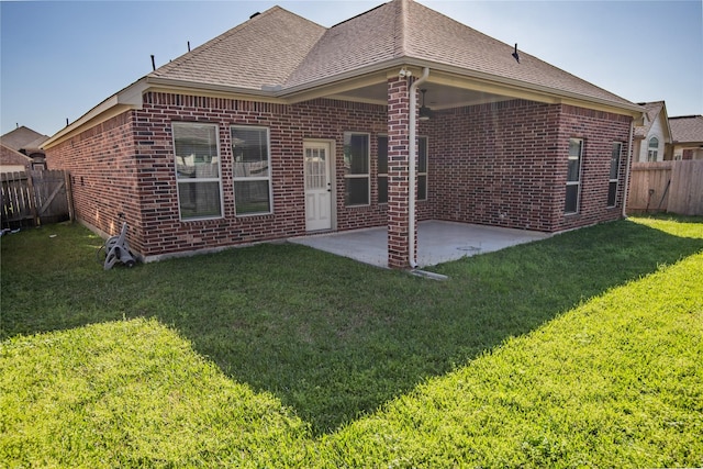 rear view of property with a patio, roof with shingles, a fenced backyard, a lawn, and brick siding