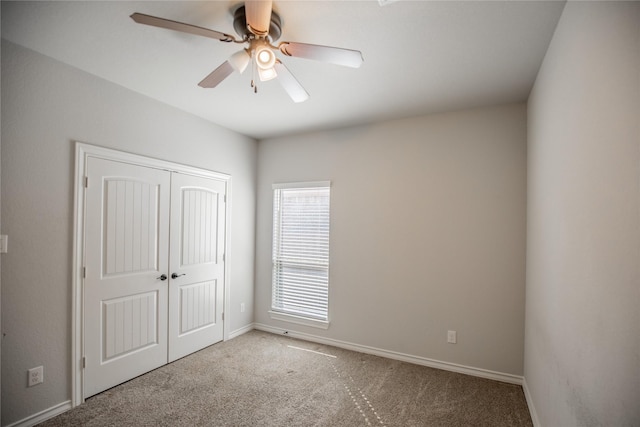 unfurnished bedroom with baseboards, a closet, carpet floors, and ceiling fan