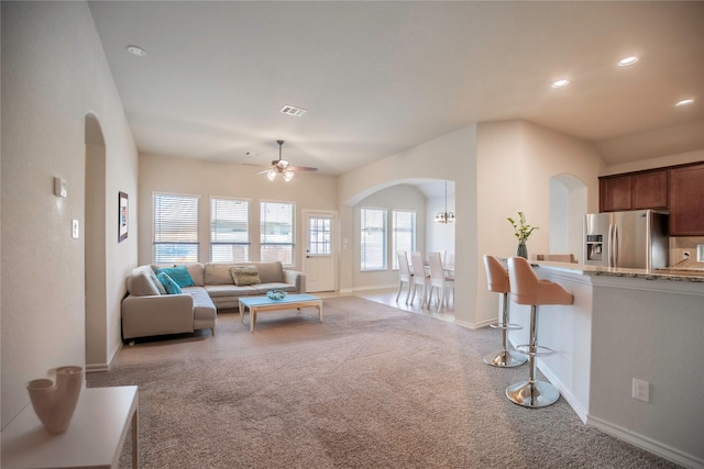 living room with arched walkways, recessed lighting, a healthy amount of sunlight, and light carpet