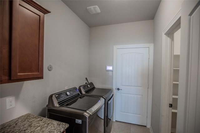 clothes washing area with light tile patterned floors, cabinet space, and independent washer and dryer