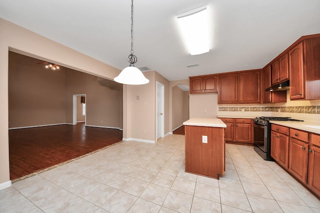 kitchen featuring range with gas stovetop, light countertops, arched walkways, and under cabinet range hood