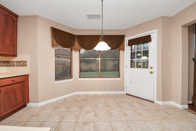 unfurnished dining area with light tile patterned flooring, visible vents, and baseboards