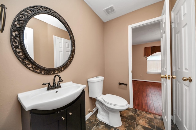 bathroom featuring visible vents, baseboards, toilet, and vanity