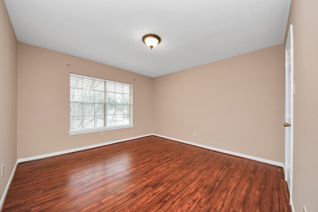 spare room featuring baseboards and dark wood-style floors