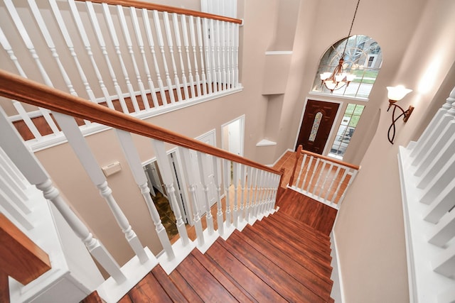 stairway featuring hardwood / wood-style floors, a high ceiling, and a chandelier