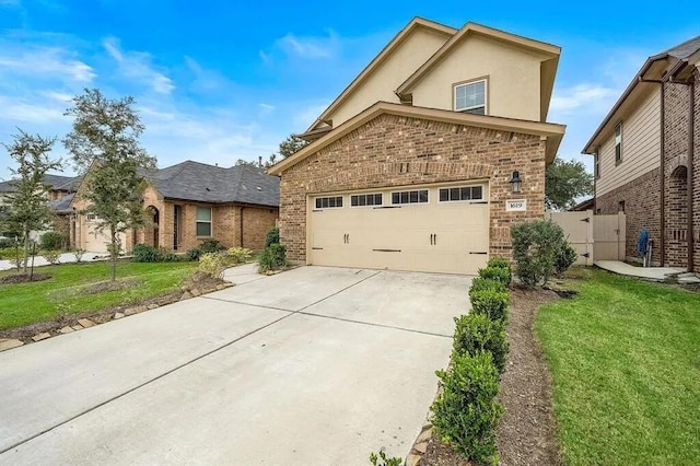 traditional home with stucco siding, driveway, a front yard, a garage, and brick siding