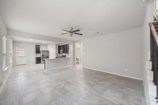 unfurnished living room with visible vents, baseboards, and ceiling fan