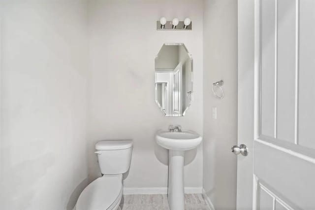 bathroom with toilet and baseboards