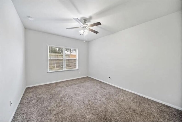 carpeted empty room featuring baseboards and a ceiling fan