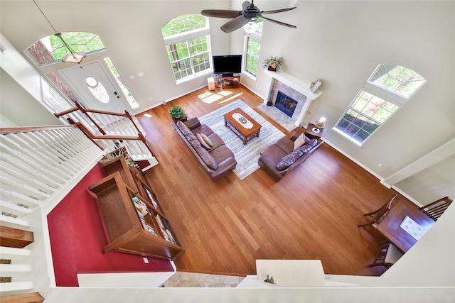 living area with a fireplace, a high ceiling, baseboards, and wood finished floors